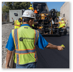 benchmark-employee-inspecting-pavement